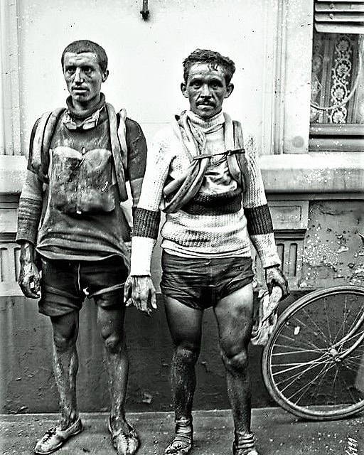 vintage cycling image of two cyclists standing at a wall looking like warriors coming from a battle