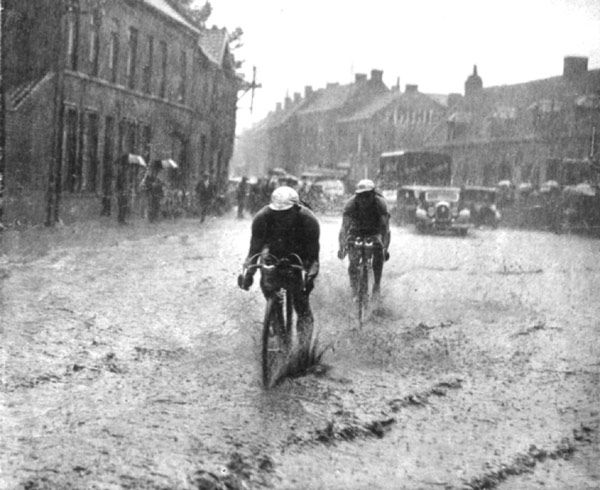 Cyclists try to cross the road in pouring rain at the Tour de France in 1936