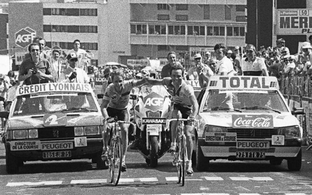 Two riders crossing the finish line together on a cycling race. 