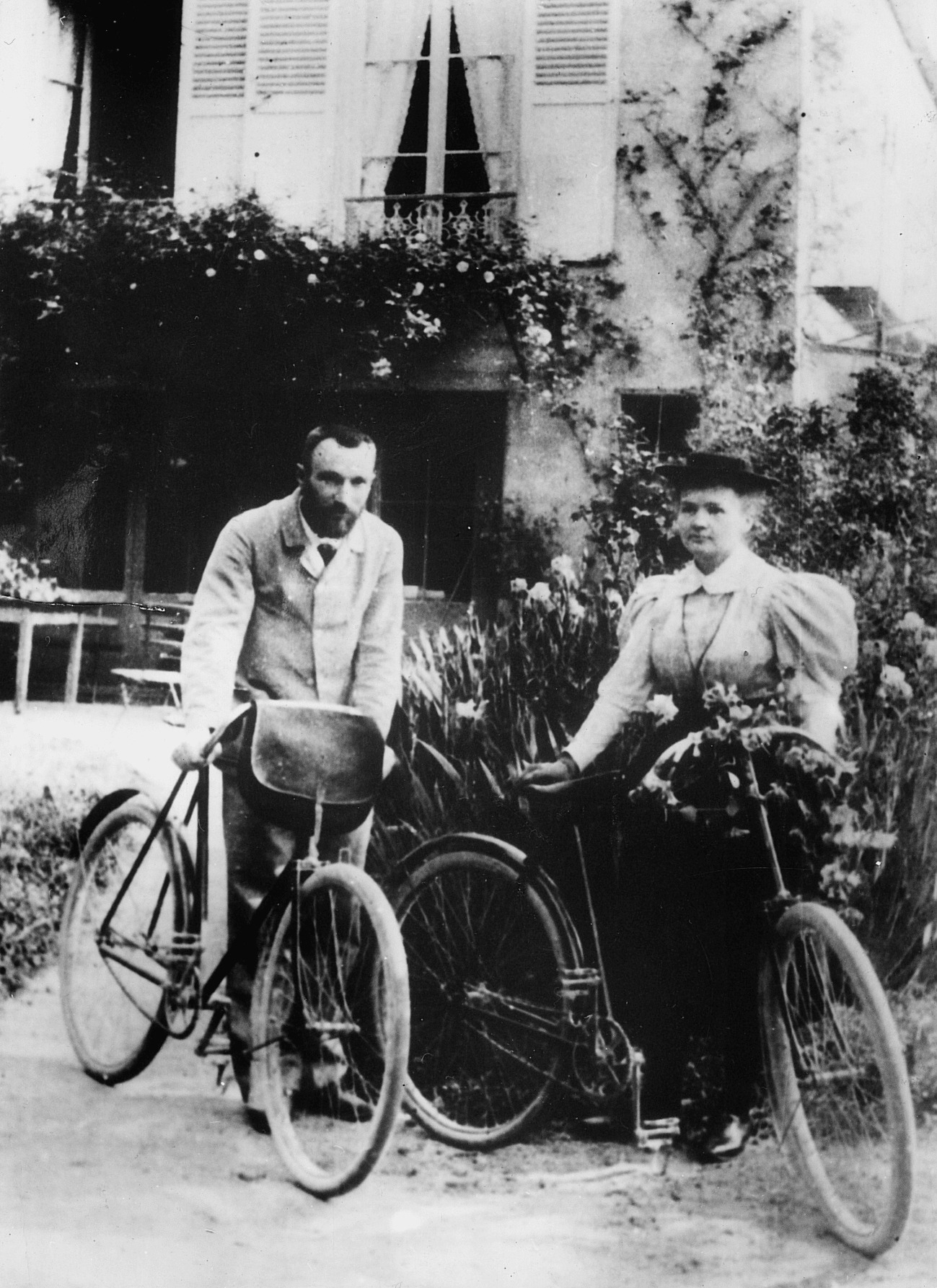 Black and white picture from 1895, when Pierre and Marie Curie are posing beside their bicycles on their honeymoon 