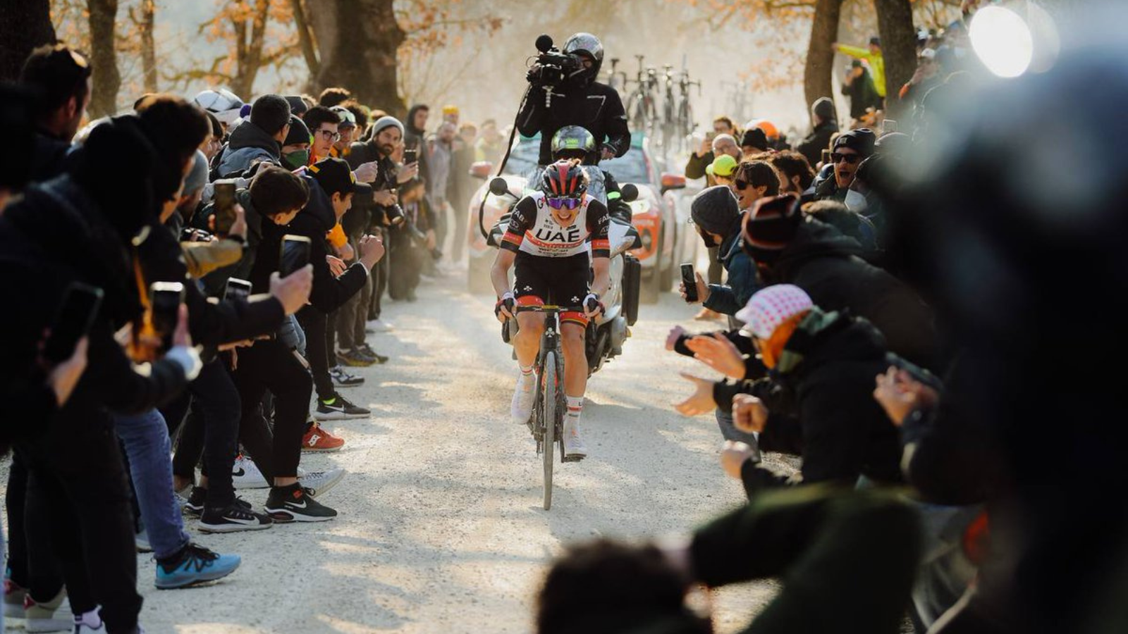 Slovenian cyclist Tadej Pogacar riding solo among cheering crowds at Strade Bianche in 2022