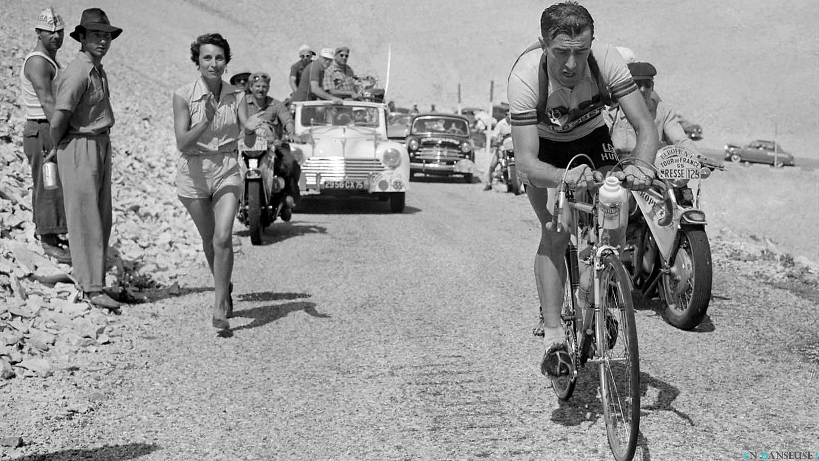 Frech multipe Tour de France winner Louison Bobet is riding solo on the mighty ascent Mont Ventoux at the Tour de Frwnce 1955. His wife Christiane is running alongside the road showing support for his husband.
