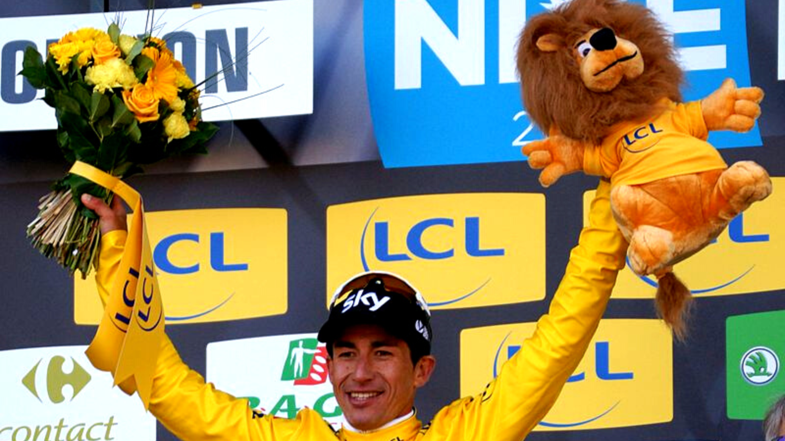 Sergio Henao winner of Paris-Nice 2017 stands on the podium in yellow jersey and with the famous yellow plush lion.