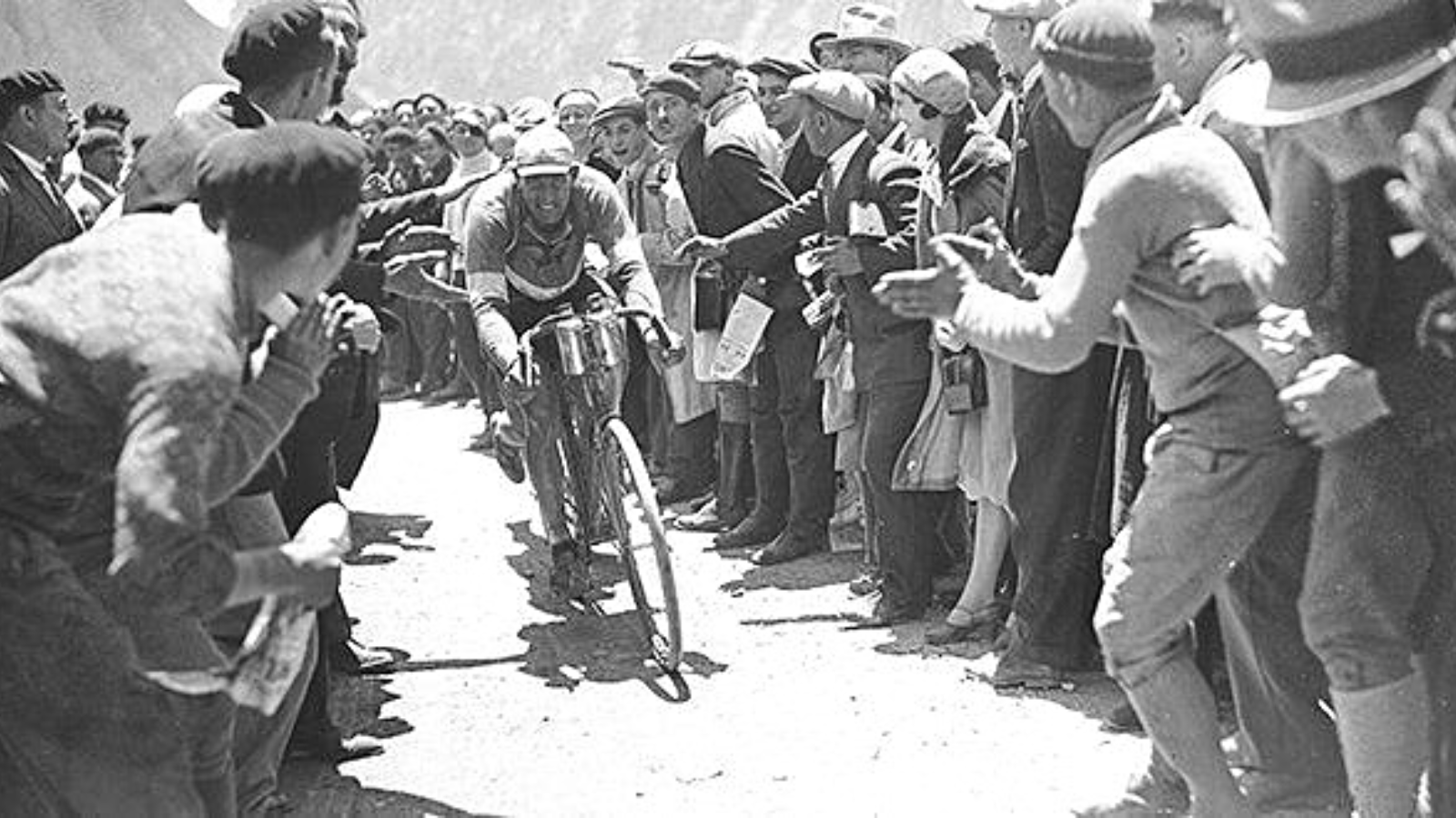 Cheering crowd supporting a cyclist in a mountain stage at Tour de France 1930