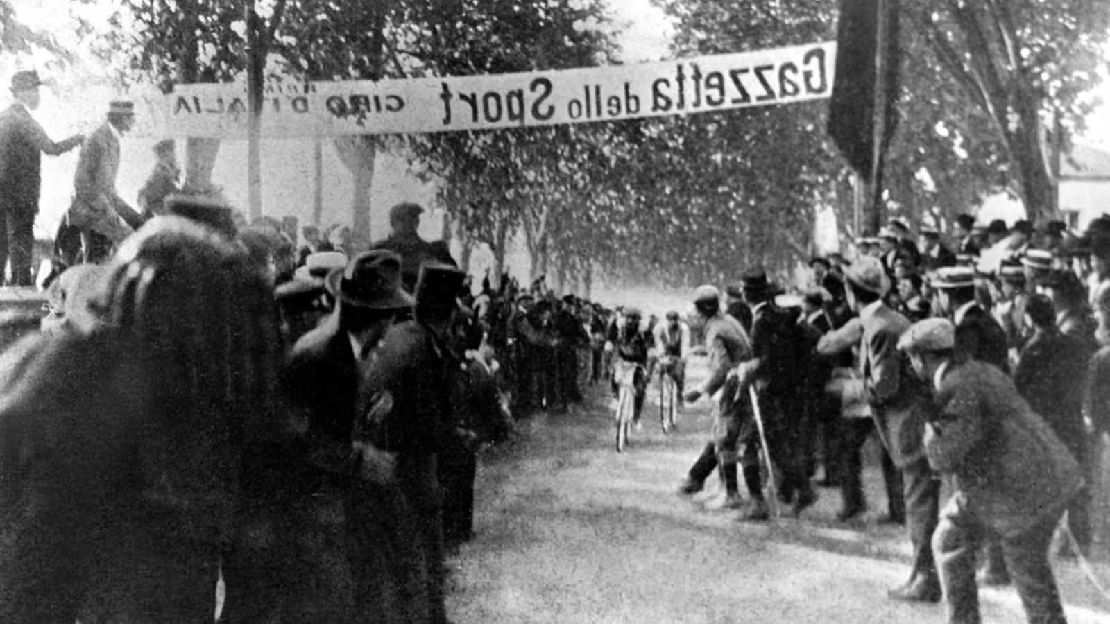 two cyclists arrive among cheering crowd at the very first Giro d'Italia in 1909