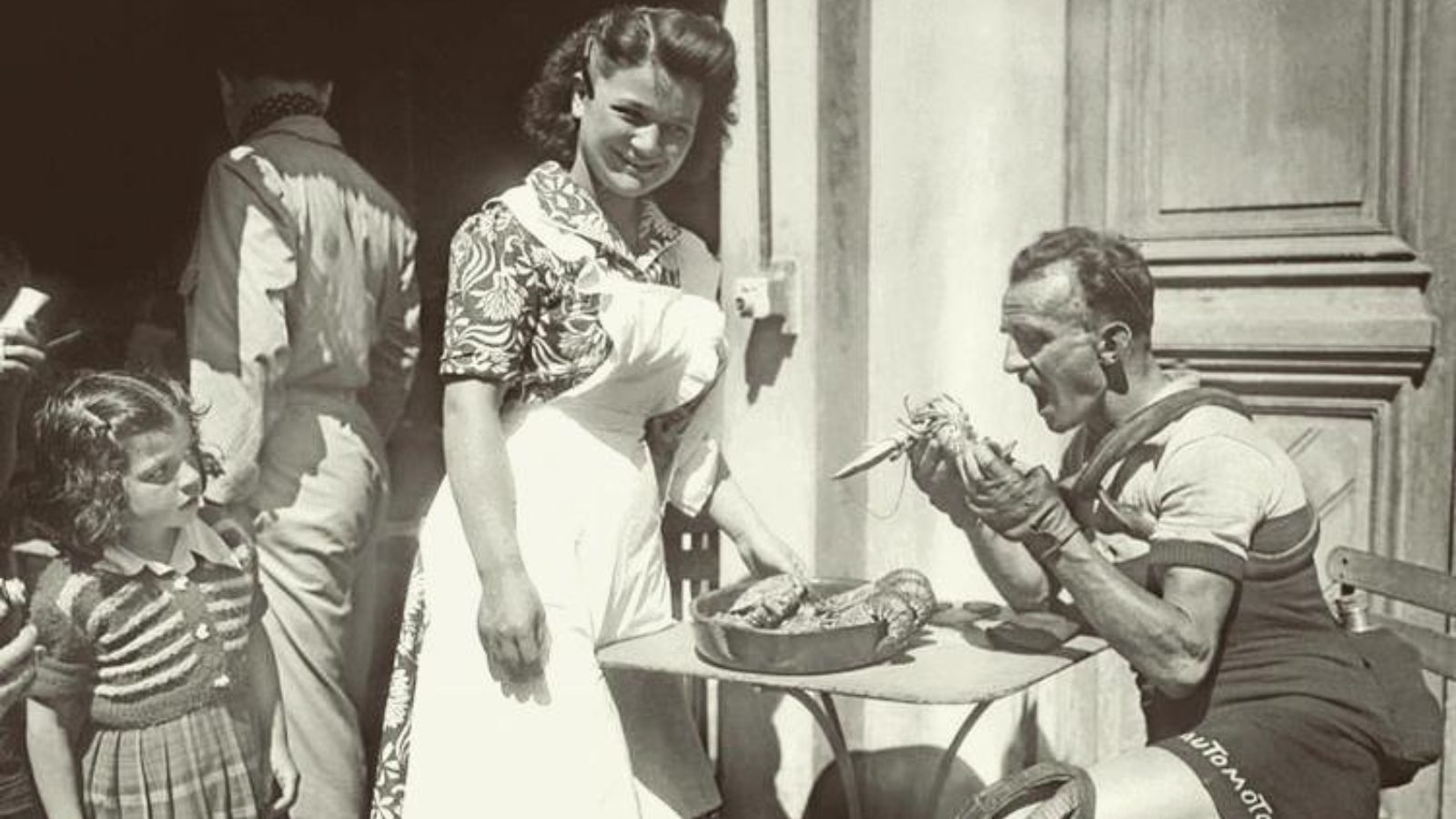 A waitress is smilong in the camera, while Tour de France winner Jean Robic eat some lobster before the 4th stage at Tour de France 1951