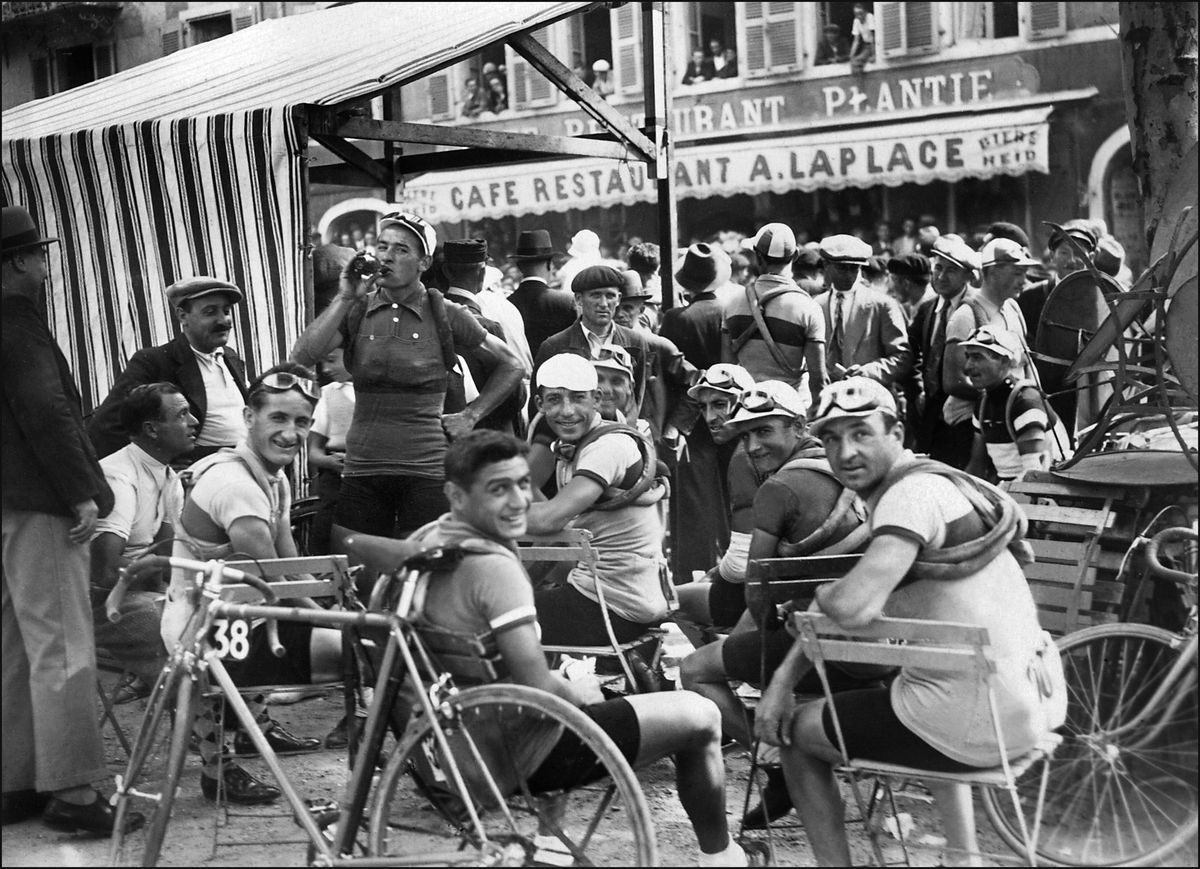 Cyclists are gathering at the outdoor table of a café in the 1930s 