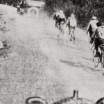 A bunch of cyclists are riding on the unpaved road during the first Giro d'Italia in 1909.